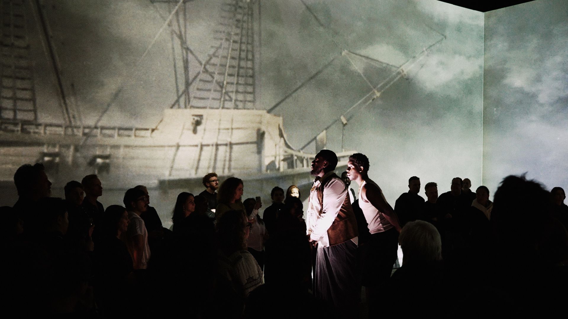 crowded room with large projected whaling ship