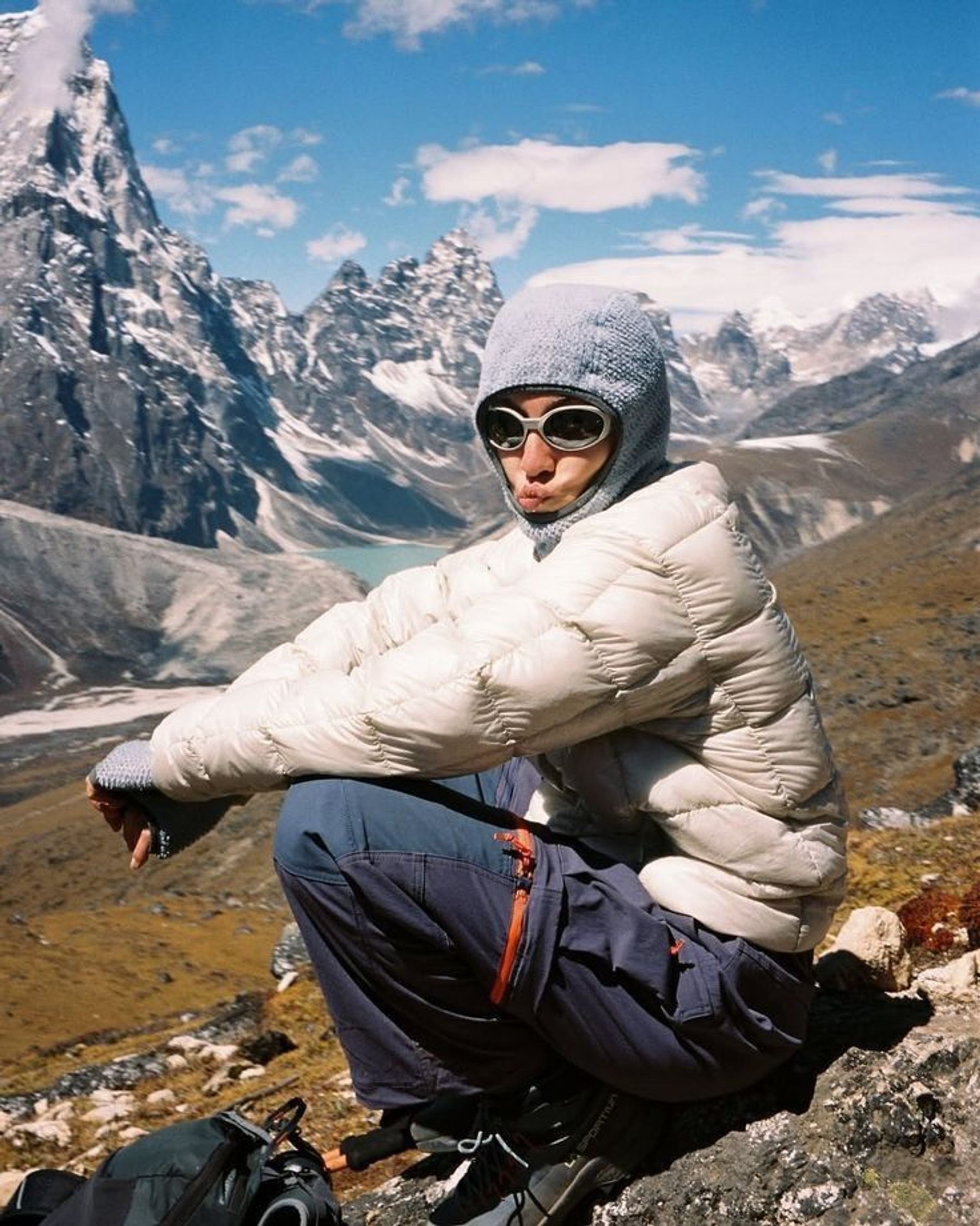 Hiker in a white jacket sitting above a mountain valley.