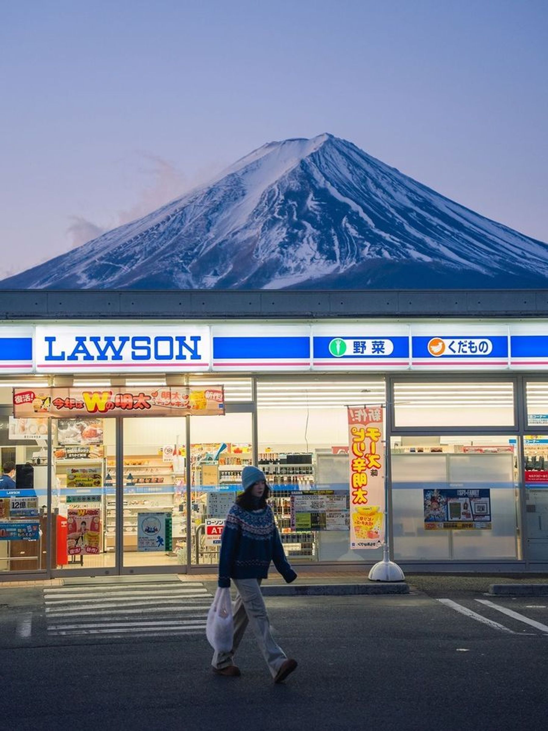 A Lawson convenience store framed by snow-covered Mount Fuji in Japan.