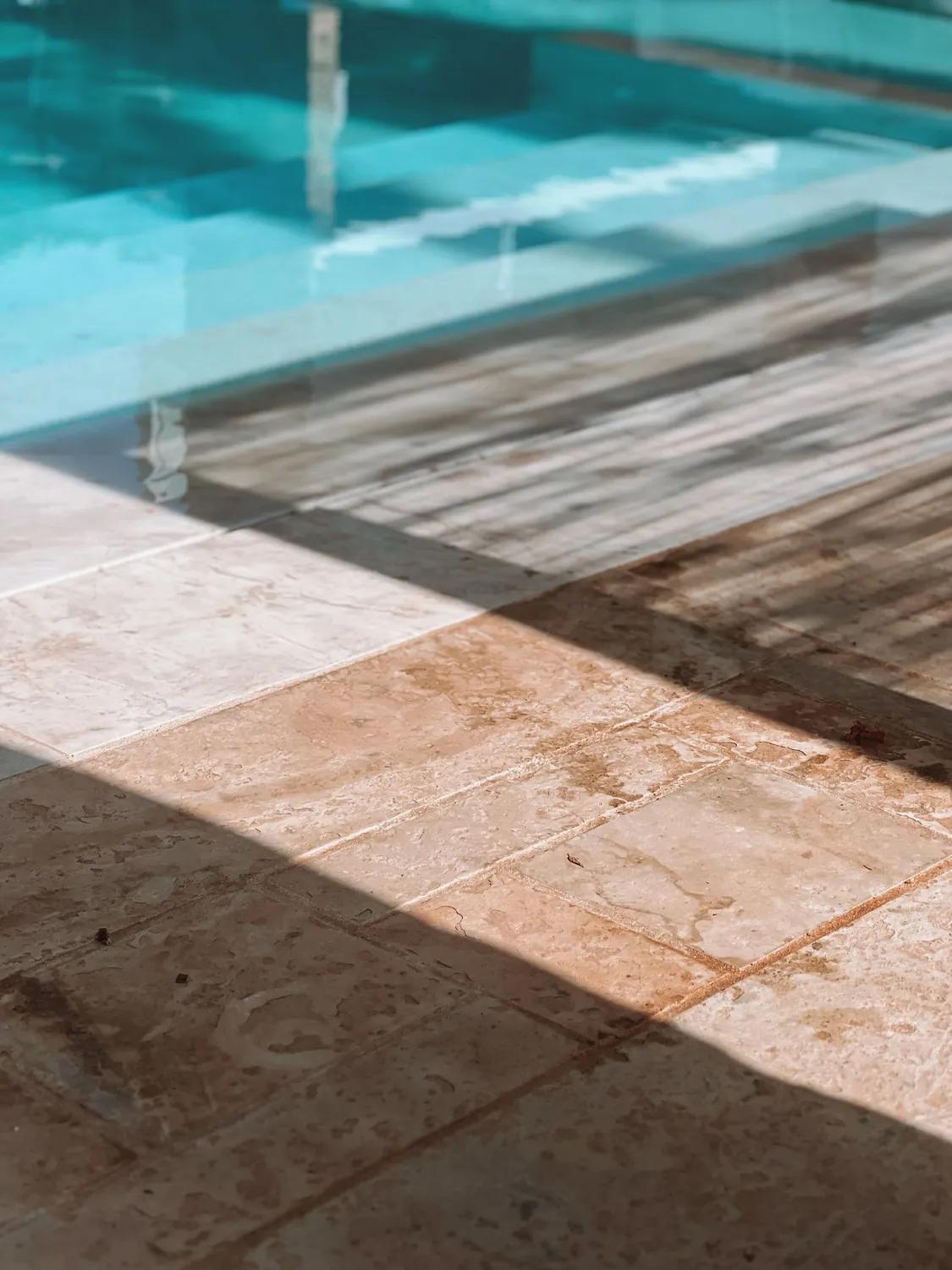 Travertine pool coping meeting clear blue water