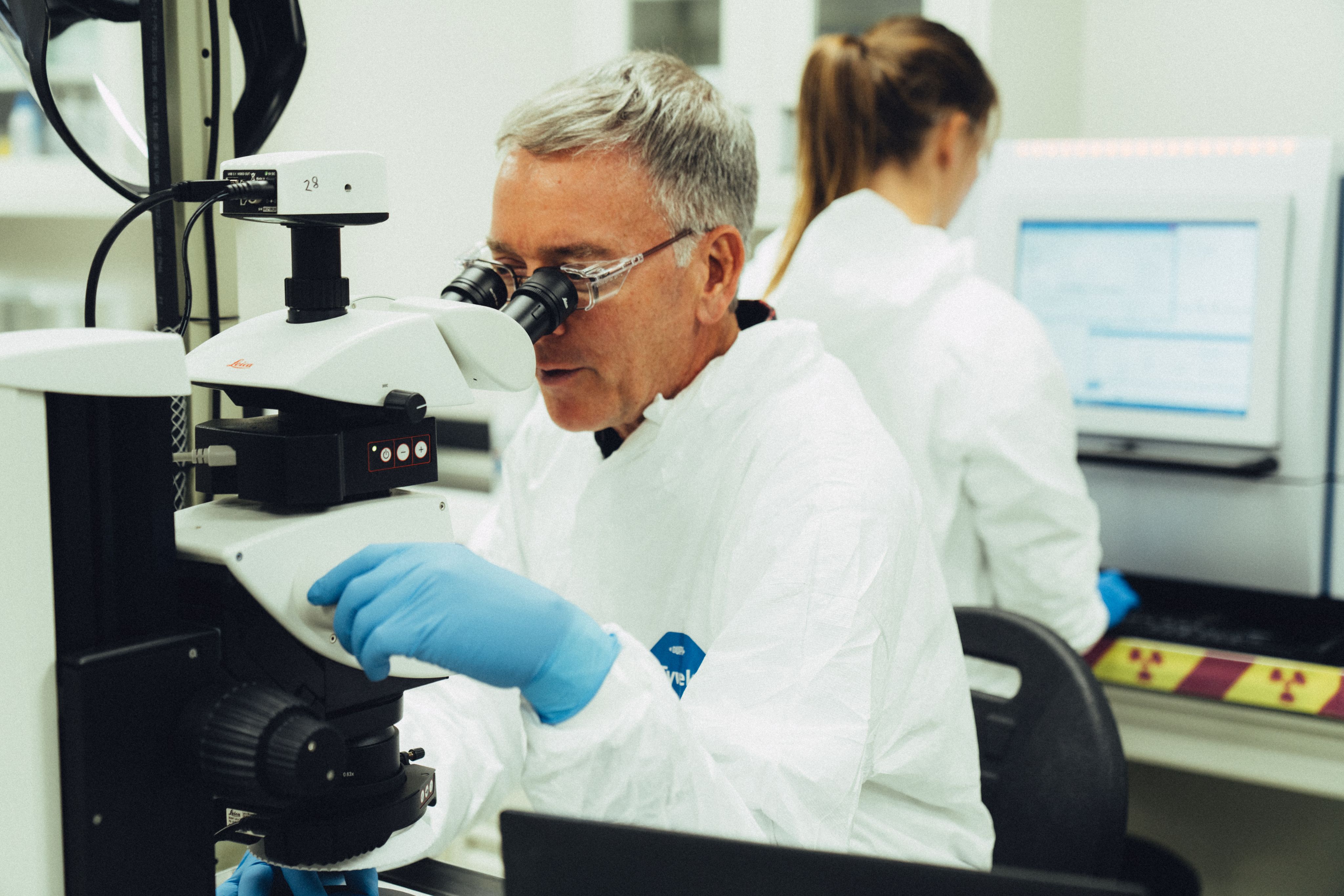 A scientist looking into a microscope in a lab