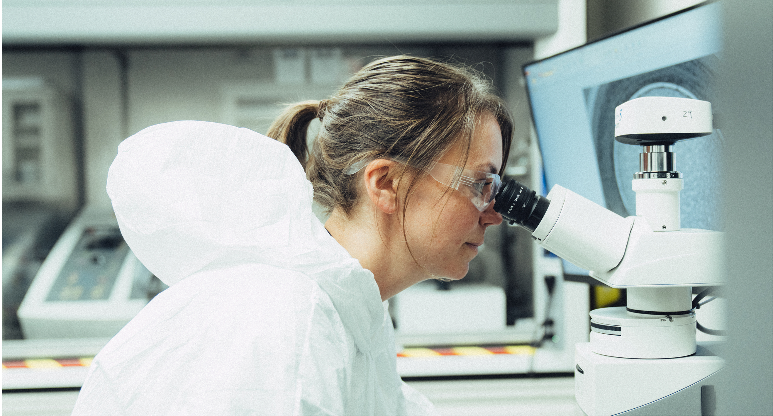 A scientist looking into a microscope in a lab