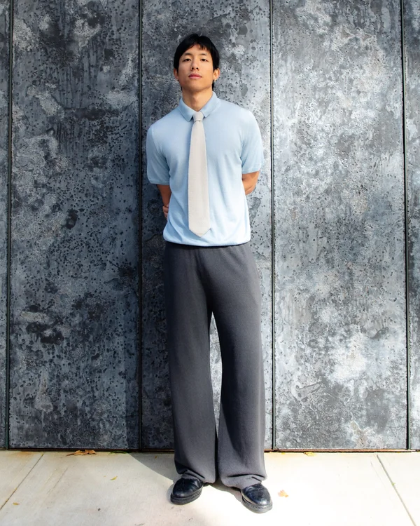 man in a city wearing cashmere pants, polo, and tie
