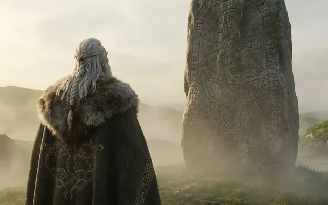 Wikingerkönig Harald Blauzahn von hinten gesehen vor einem großen Runenstein in nebliger Morgenlandschaft
