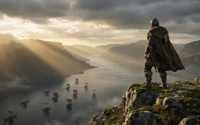 A Viking chieftain standing on a rocky cliff overlooking a vast fjord landscape with longships sailing below