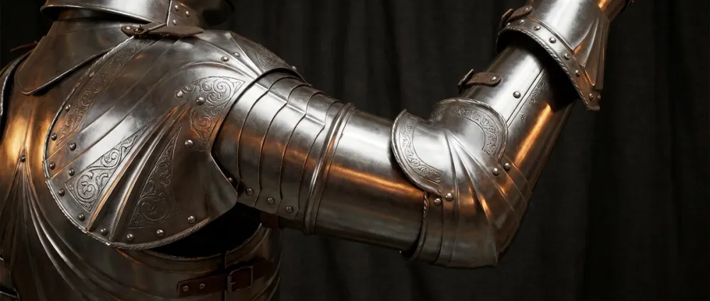 Close-up of polished European plate armor showing articulated joints at elbow and shoulder Close-up of polished European plate armor showing articulated joints at elbow and shoulder