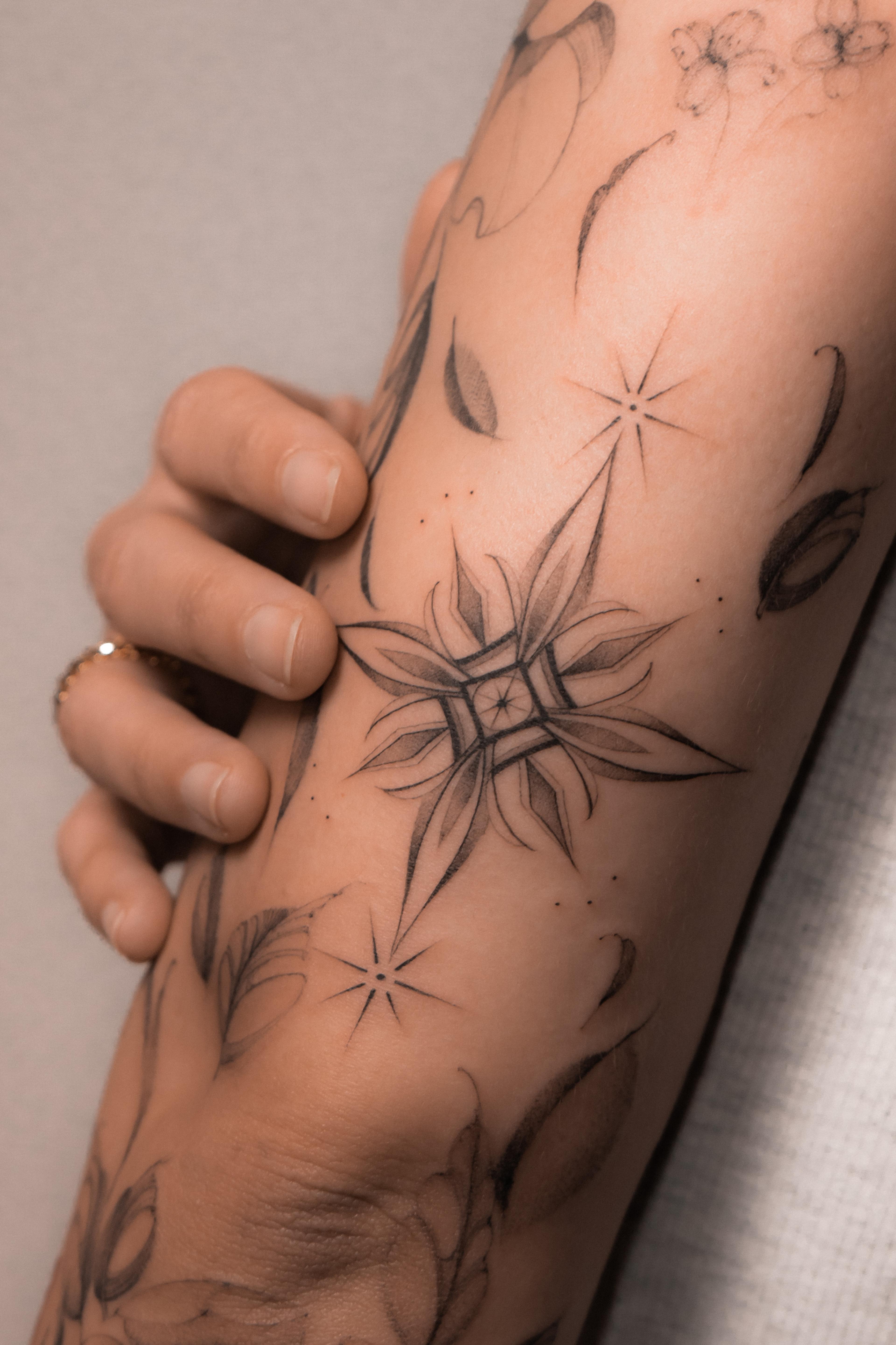 Geometric ornament with fine leaves and dotwork on the forearm