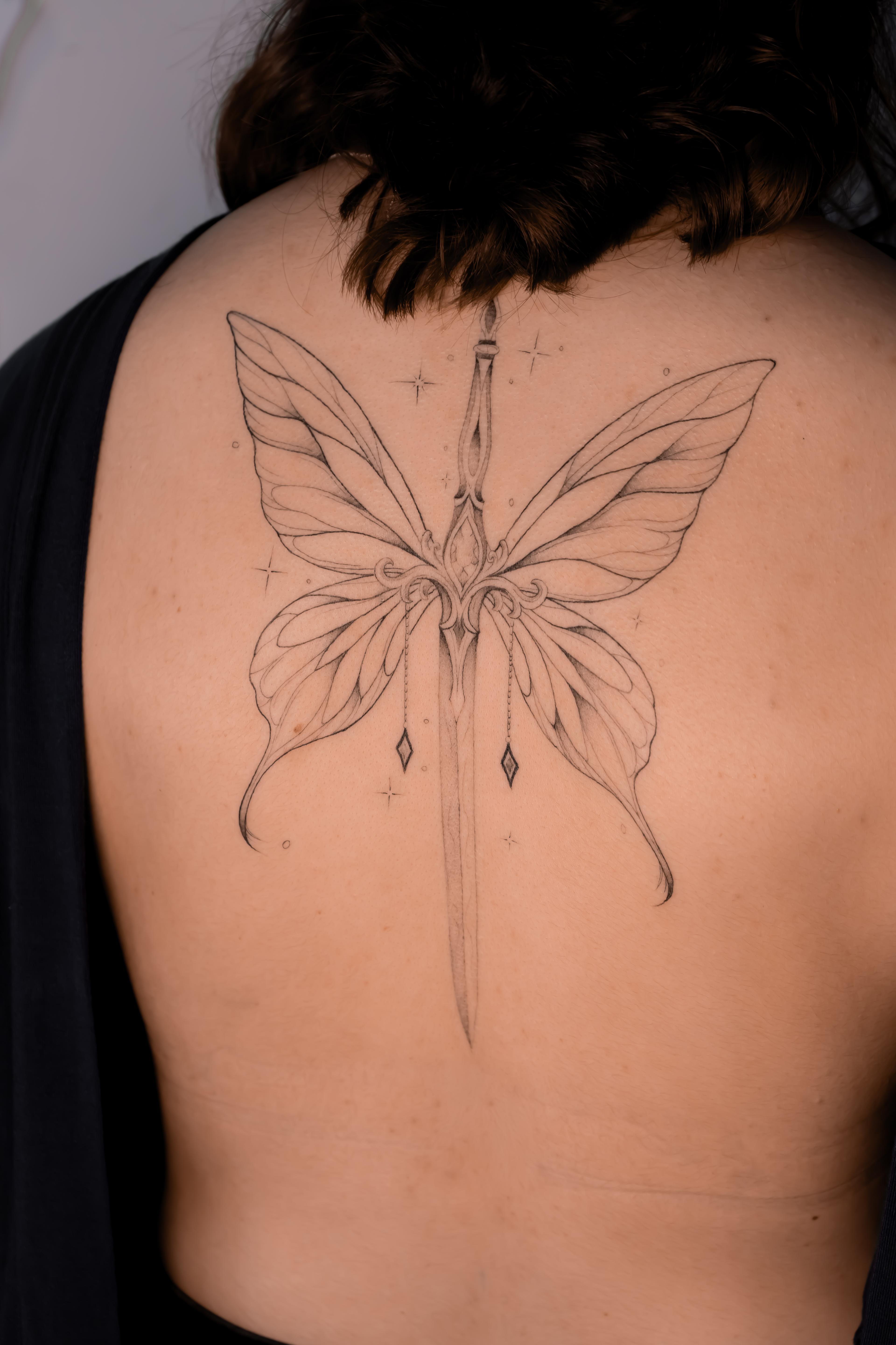 Symmetrical fine-line butterfly and sword tattoo centered along the back