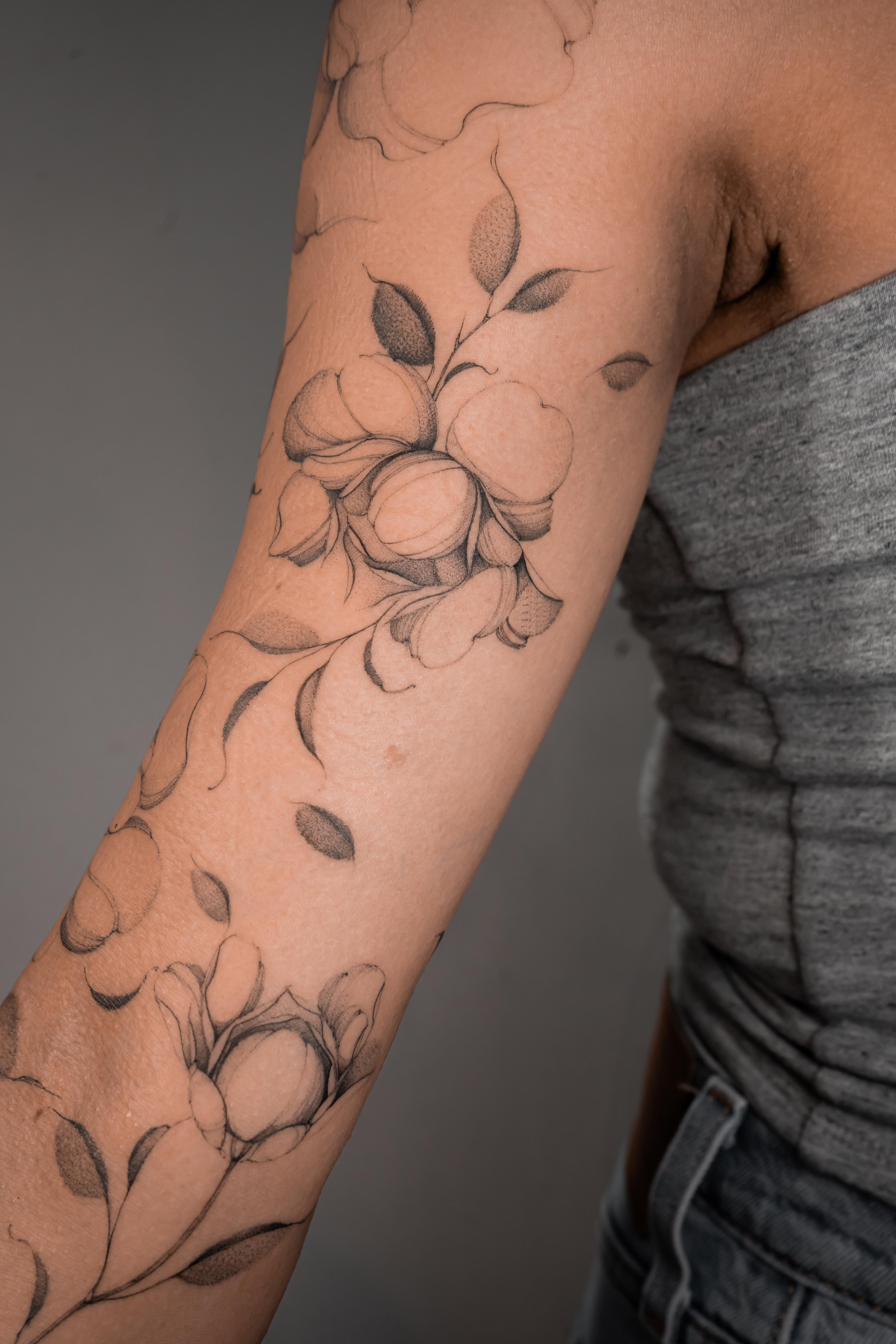 Fine-line peonies and shaded leaves flowing along the full arm