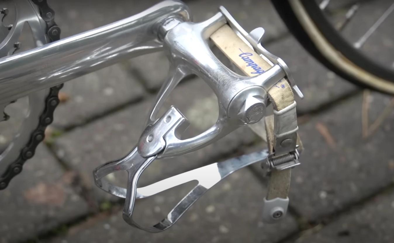 Before clipless pedals riders would strap their feet to the pedals using 'toe clips' 