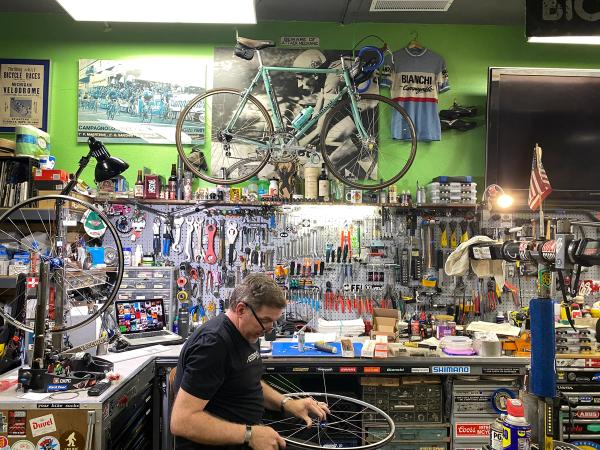 Jim Potter, the shop owner, works on a wheel in front of his work stand and a 1981 Bianchi from his person collection