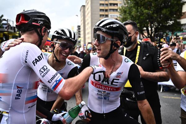 Adam Yates celebrates winning stage 1 of the 2023 Tour de France with teammates Tadej Pogačar (left) and Rafał Majka (centre)