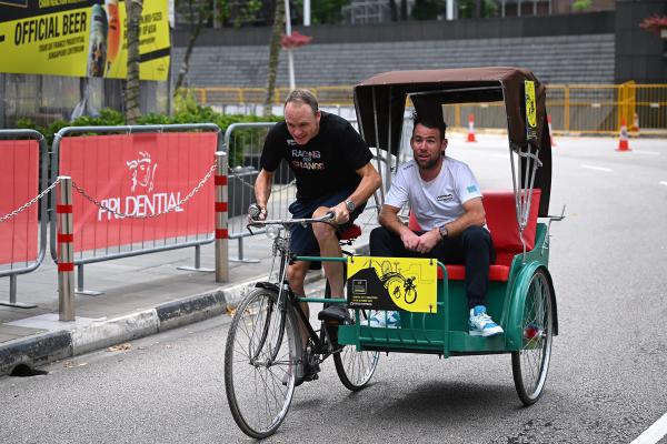 Mark Cavendish enjoys the ride as Chris Froome rides the rickshaw relay