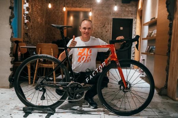 Chris Froome kneels behind the eye-catching bike during his recent visit to the Factor manufacturing facility
