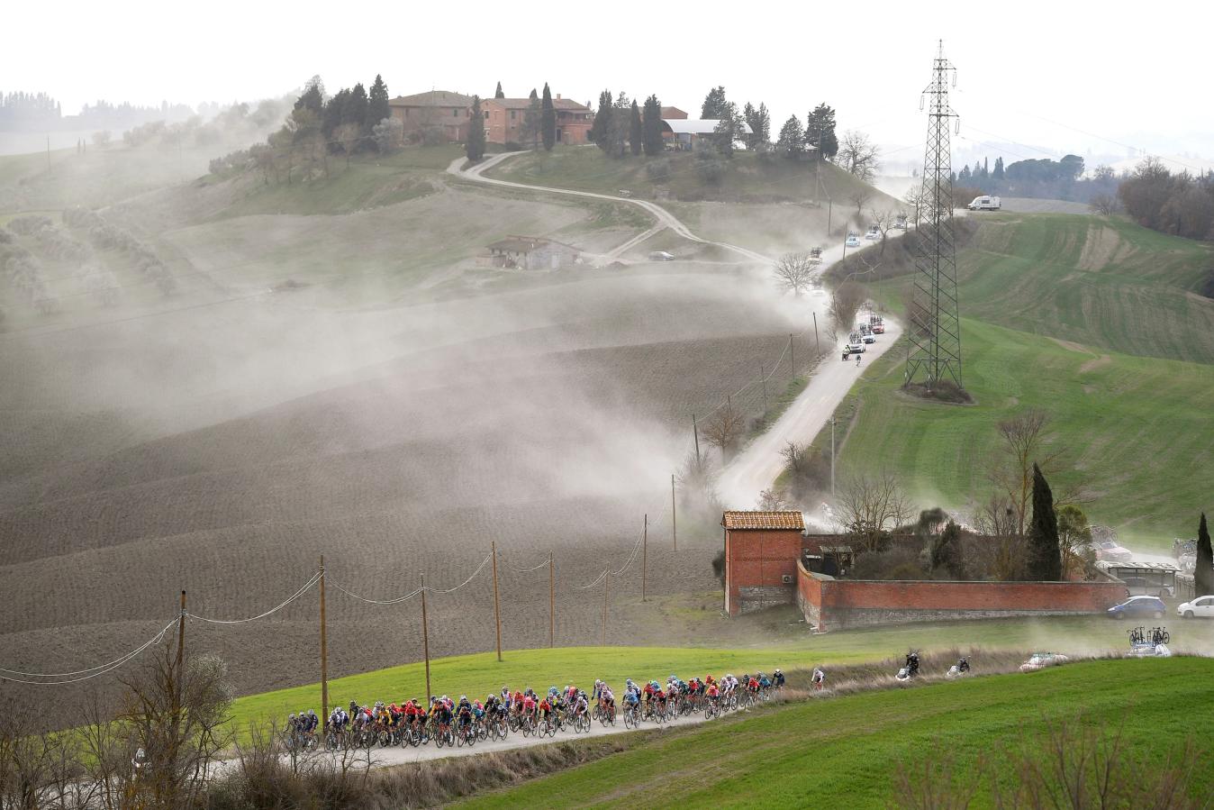 The riders kick up clouds of dust as they tackle the gravel tracks of Strade Bianche 