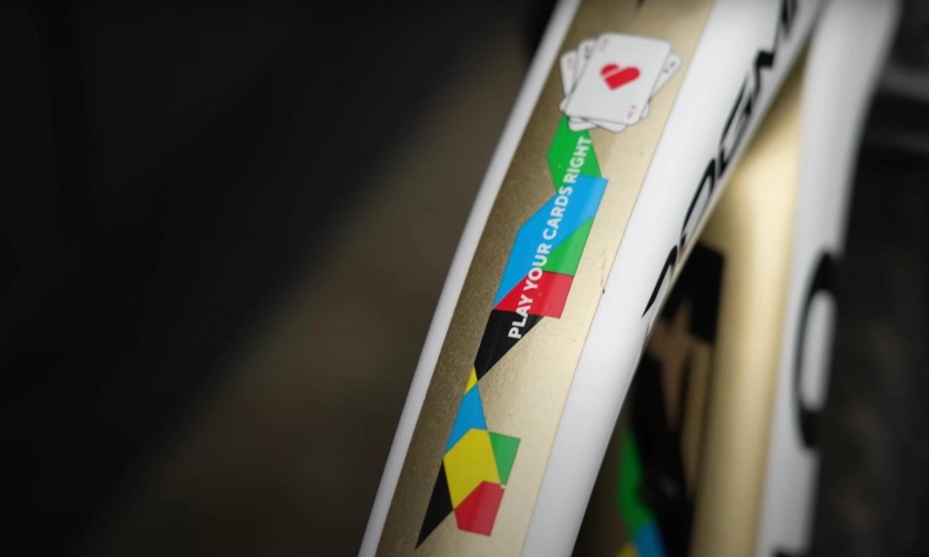 The top tube of the bike features the motto 'play your cards right' 