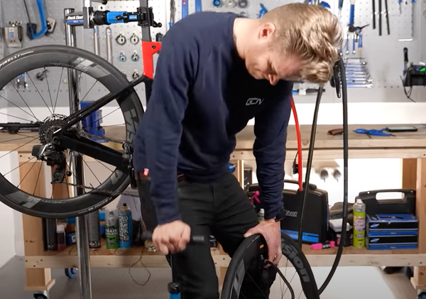 GCN presenter Oliver Bridgewood inflating a tyre with a track pump
