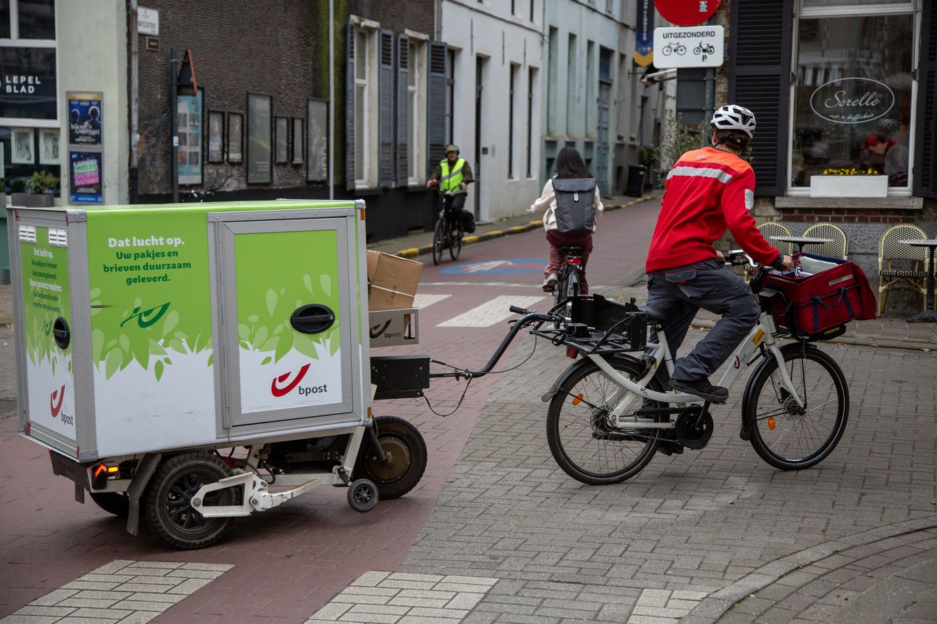 A postal worker tows an electrically assisted trailer through Gent
