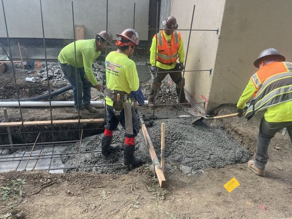 Three-person crew pouring and finishing concrete slab