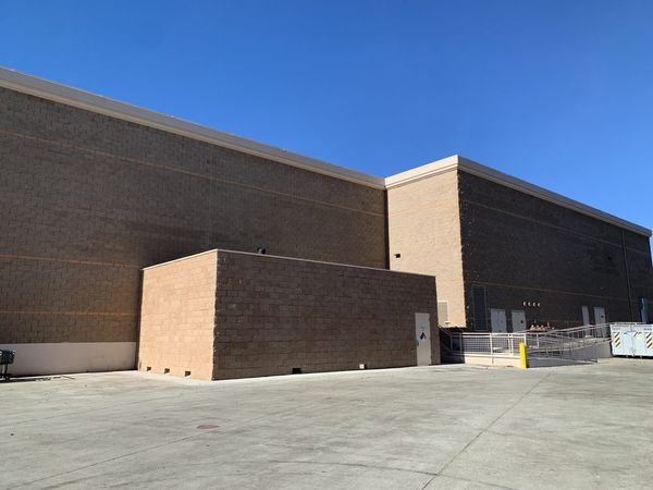 Completed commercial building exterior — brown panel facade, blue sky