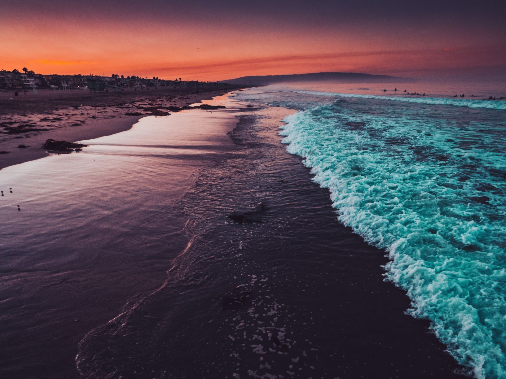 An overhead view of a beach at dusk with waves crashing
