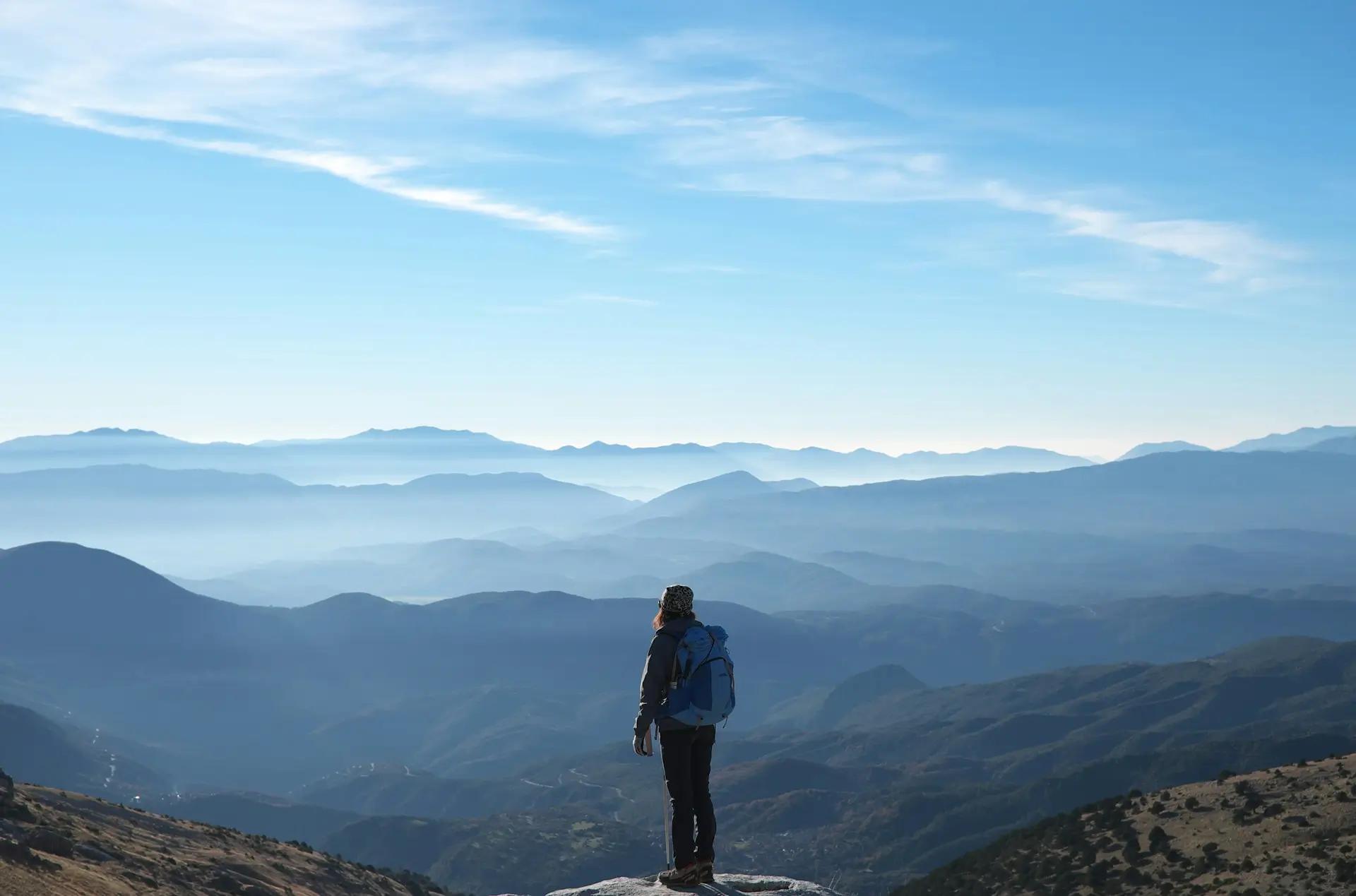 A hiker looking across a mountain range vista