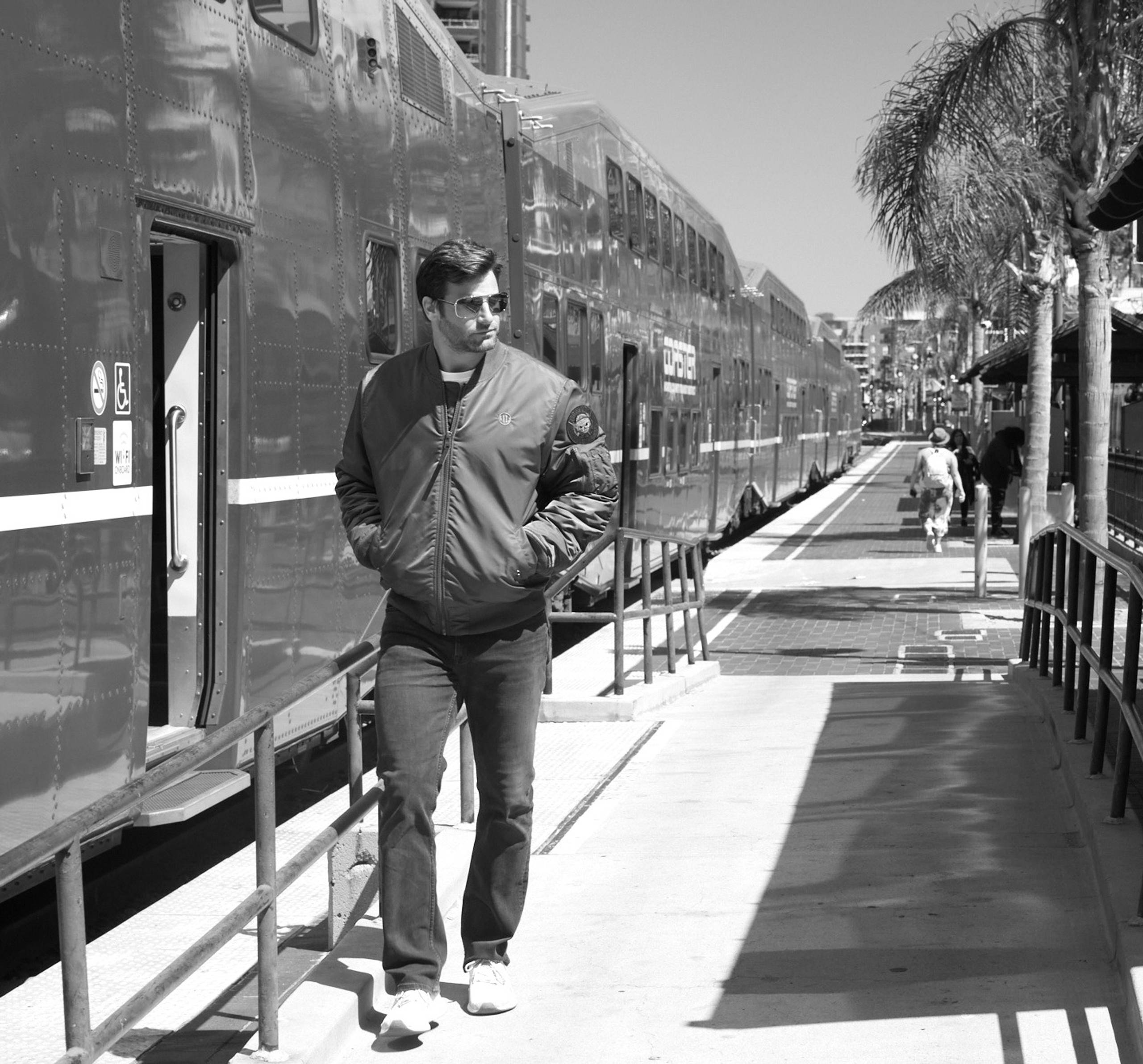 Man in a jacket walking past a train on a platform