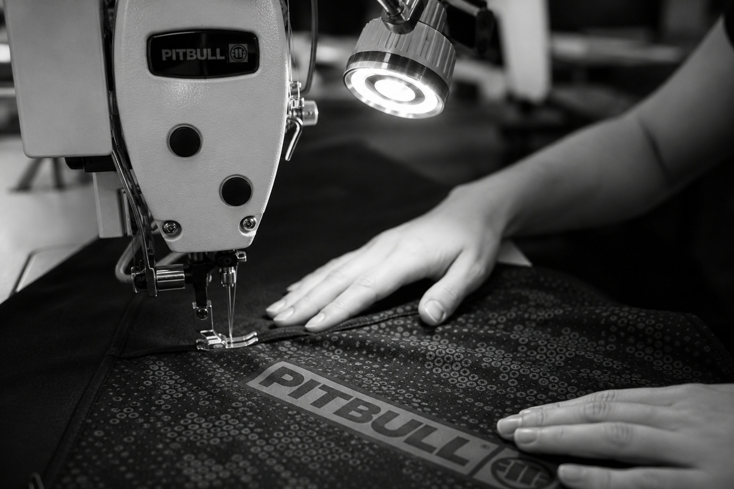 Sewing fabric with PITBULL logo on a sewing machine