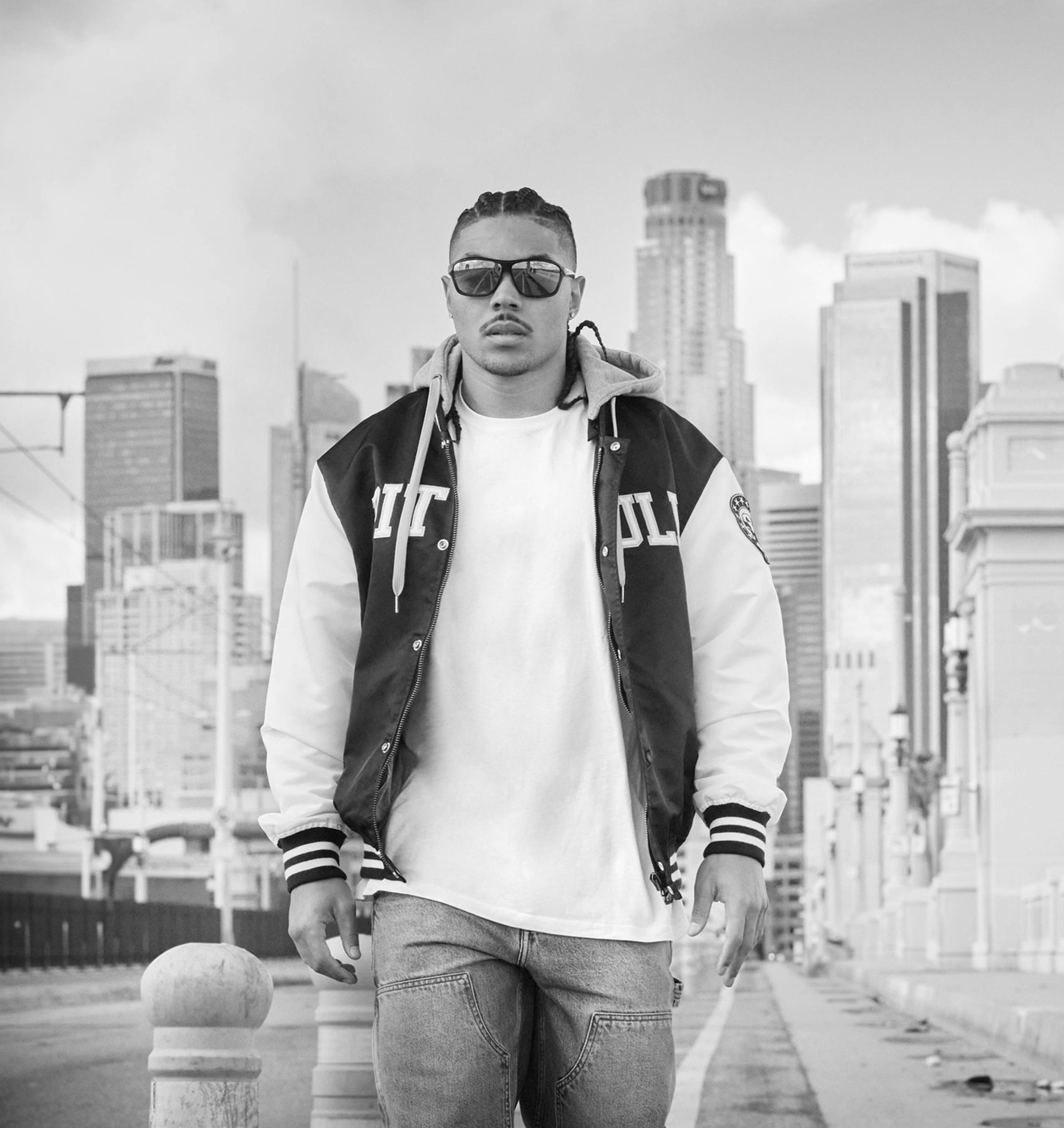Mann in zweifarbiger Collegejacke auf einer Stadtbrücke