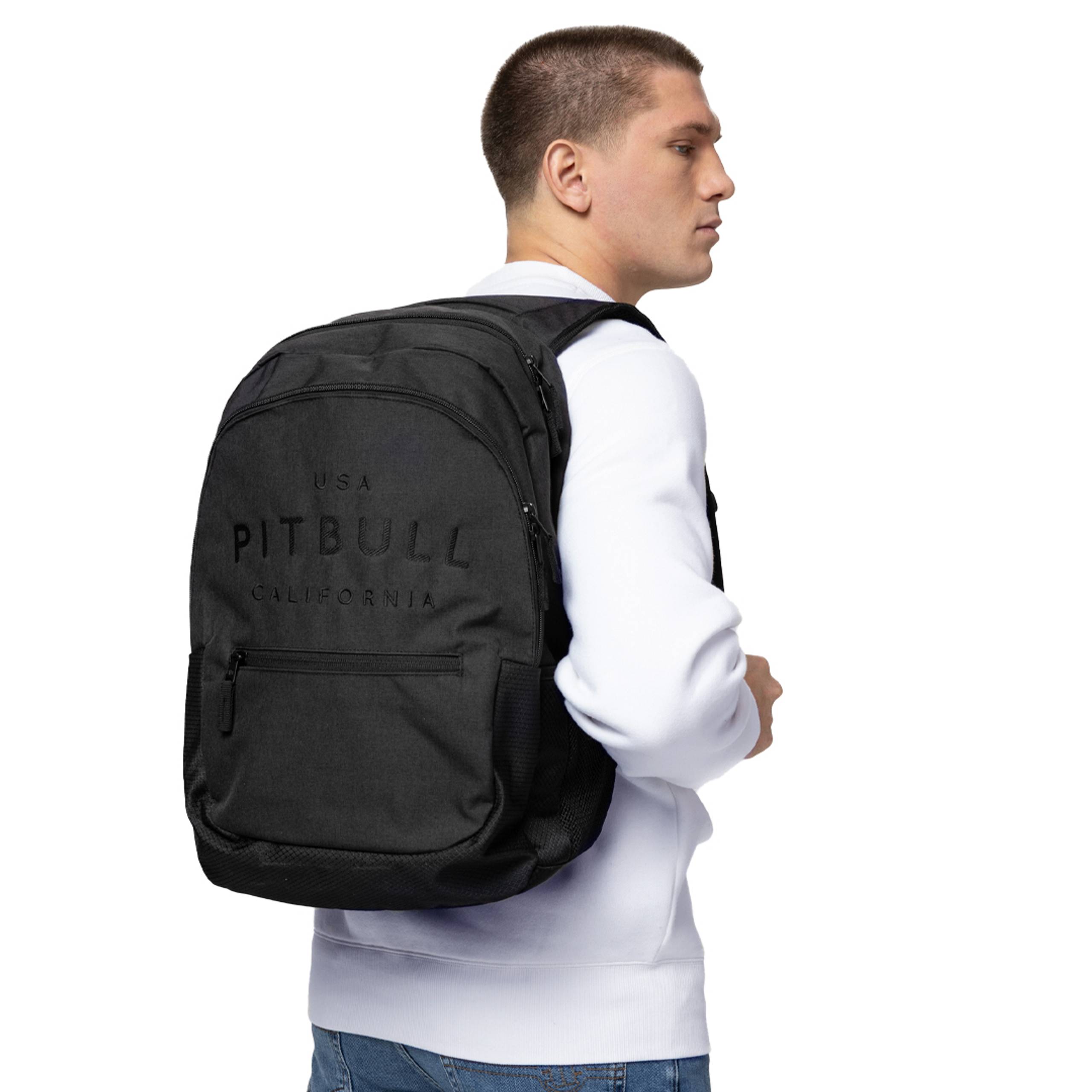 Man in a white sweatshirt wearing a black Pitbull backpack