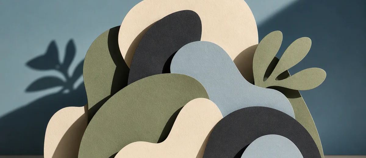Overlapping ivory, charcoal and sage paper cutouts casting contrasting shadows.