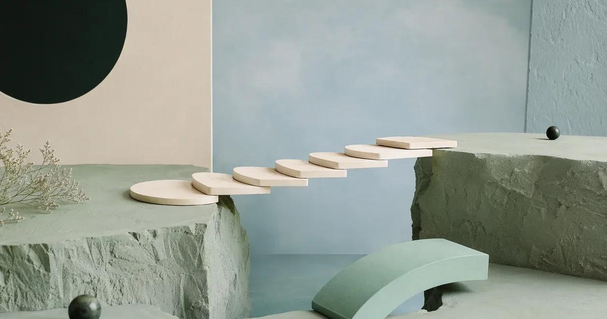 An architectural model of ivory stepping platforms spans a gap, with the final mint bridge section resting nearby awaiting placement.