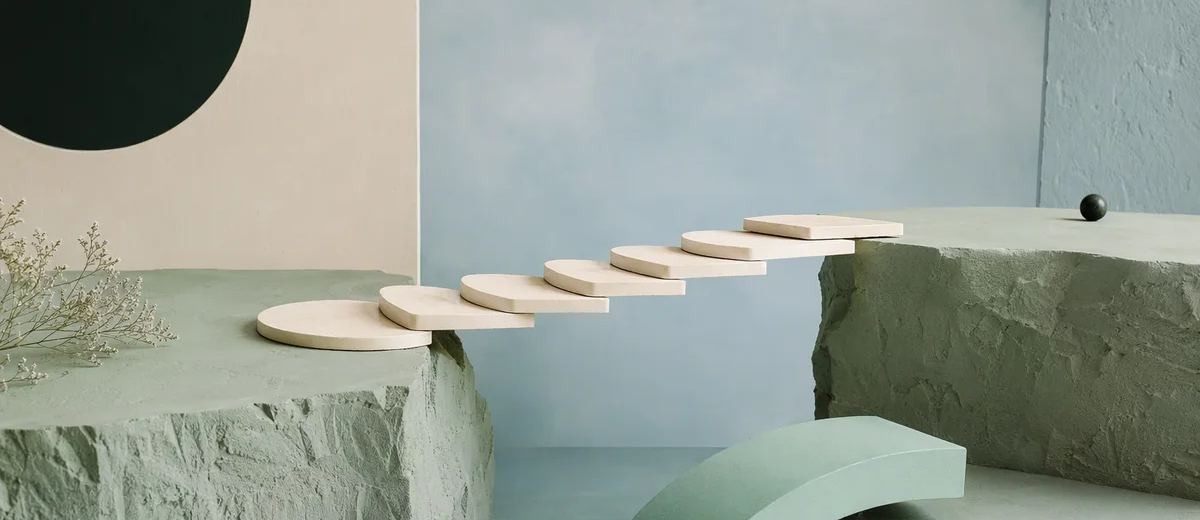 An architectural model of ivory stepping platforms spans a gap, with the final mint bridge section resting nearby awaiting placement.