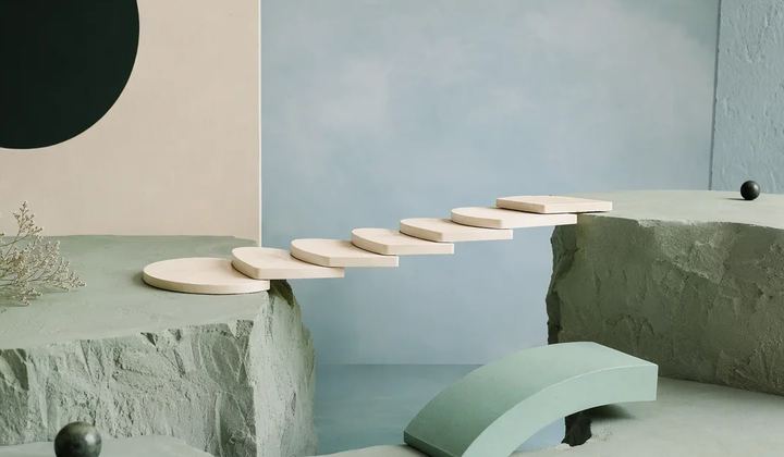 An architectural model of ivory stepping platforms spans a gap, with the final mint bridge section resting nearby awaiting placement.