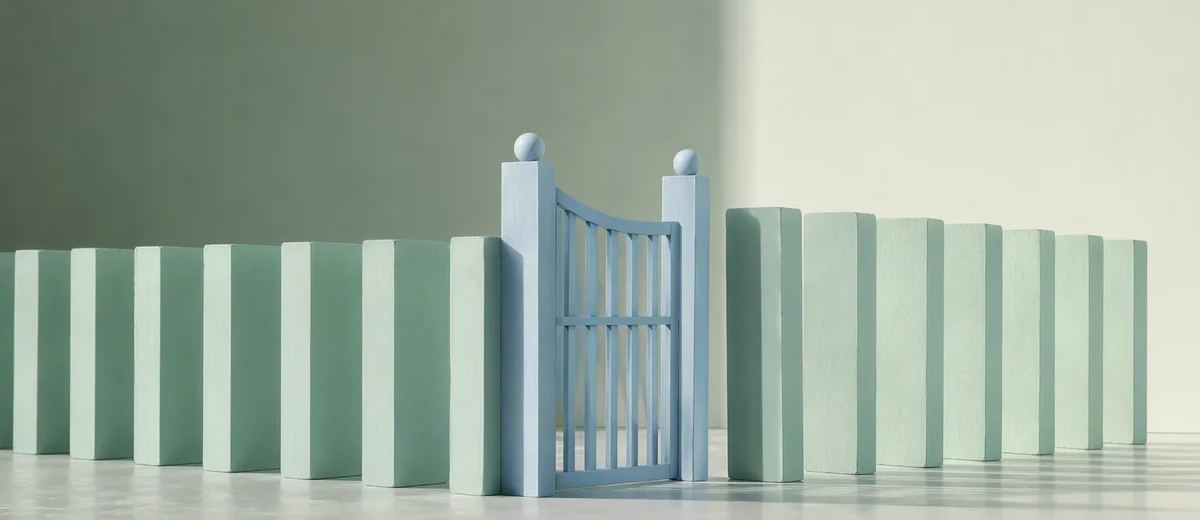 A carefully arranged line of mint domino-like architectural blocks stands beside a pale blue gate that interrupts their path.