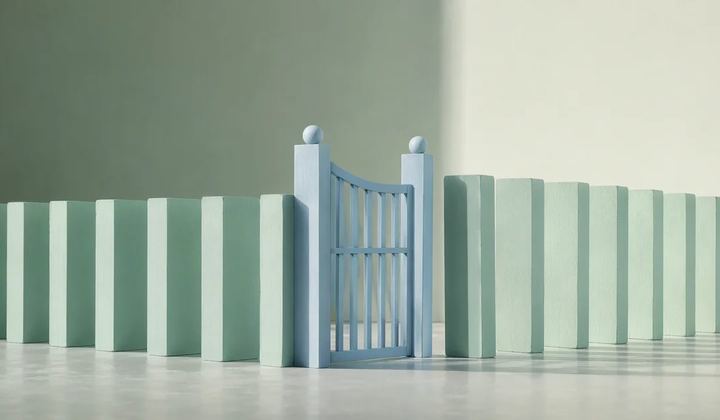 A carefully arranged line of mint domino-like architectural blocks stands beside a pale blue gate that interrupts their path.