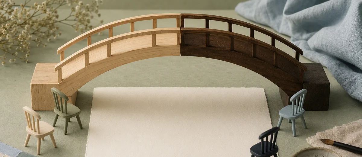 A two-tone wooden model bridge spans a blank card surrounded by miniature chairs.