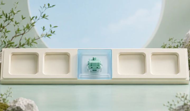 A mint component sits behind a transparent blue panel in the center of an ivory display with empty recesses.