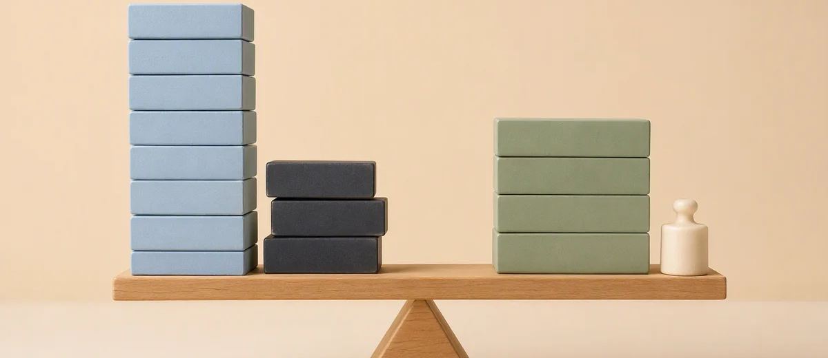 Blue, charcoal and sage blocks sit on a wooden balance board beside a small wooden figure.