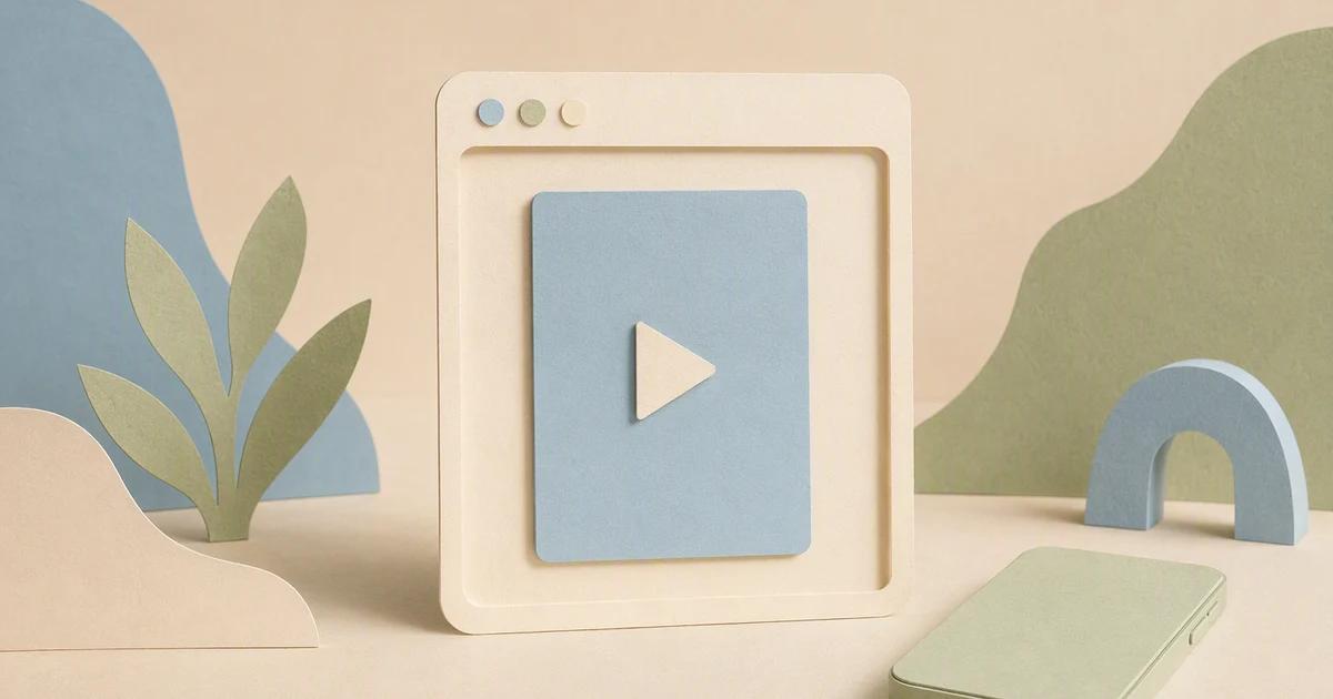 An open browser-shaped paper frame holds a simple video card while a phone rests to one side.