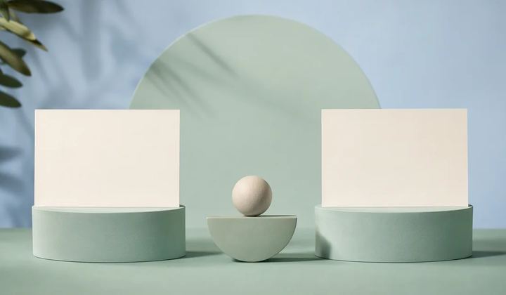 Two unmarked ivory editorial cards on equal mint pedestals under balanced pale blue studio lighting, with a small central balance form
