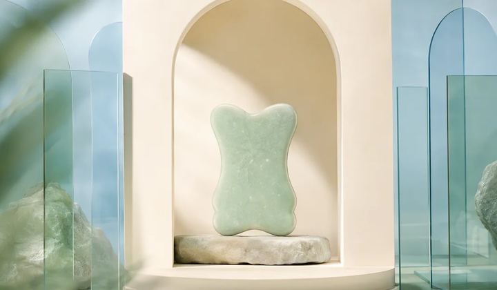 A rounded mint sculpture rests on a stone pedestal inside an ivory arch, surrounded by translucent blue panels.