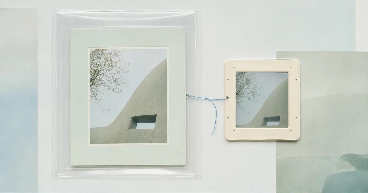 A photographic print in a transparent sleeve linked by blue thread to a smaller framed copy.