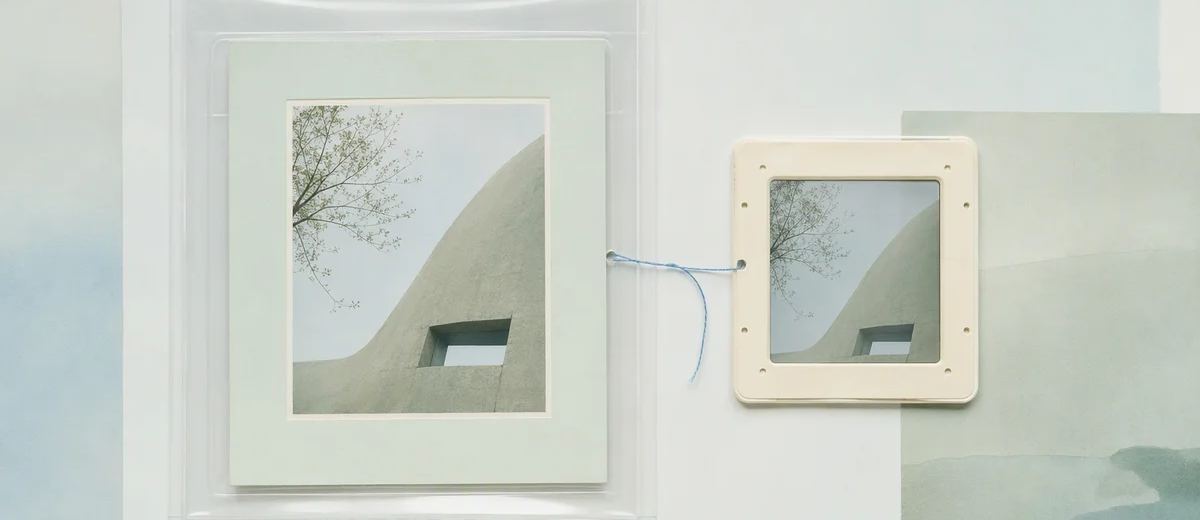 A photographic print in a transparent sleeve linked by blue thread to a smaller framed copy.