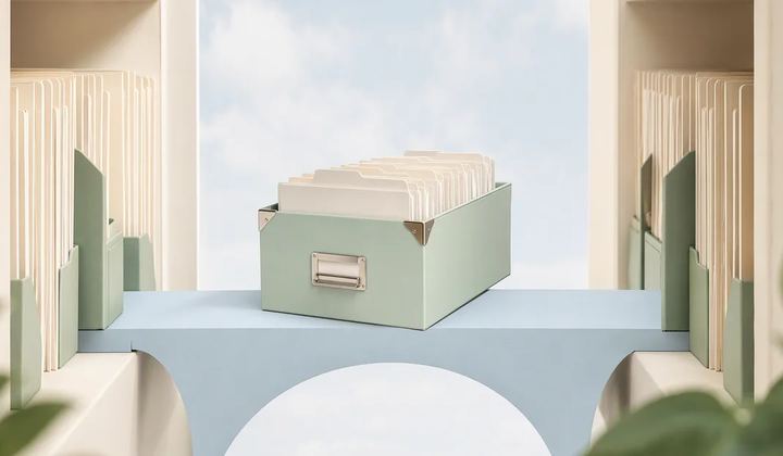 A mint archive box filled with ivory folders rests on a pale blue bridge between two ivory shelves.
