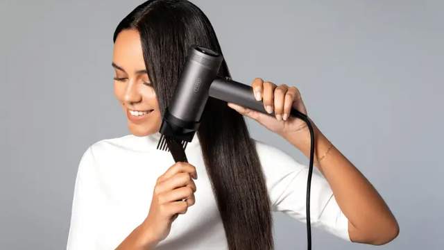A women with dark hair blow drying her hair