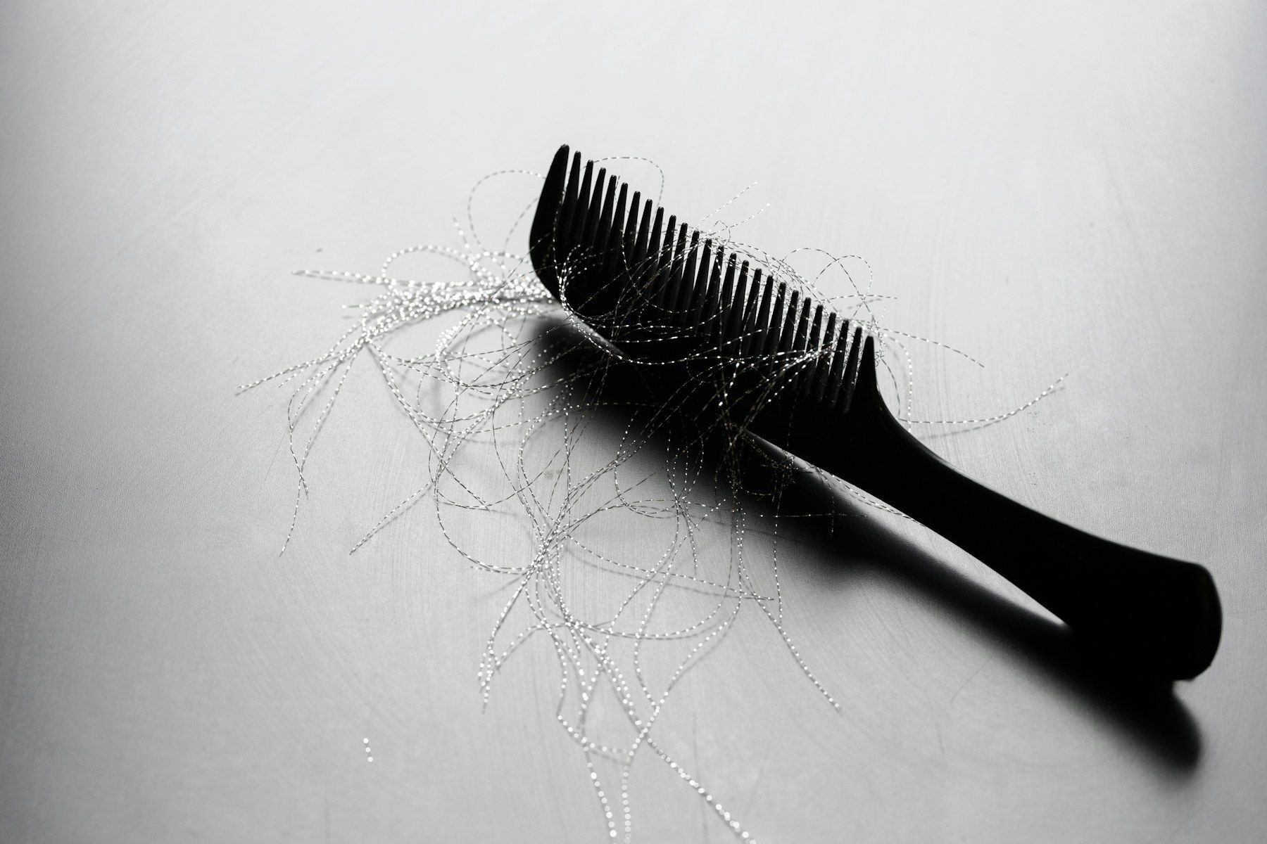 Black comb on a gray surface with loose strands of shed hair