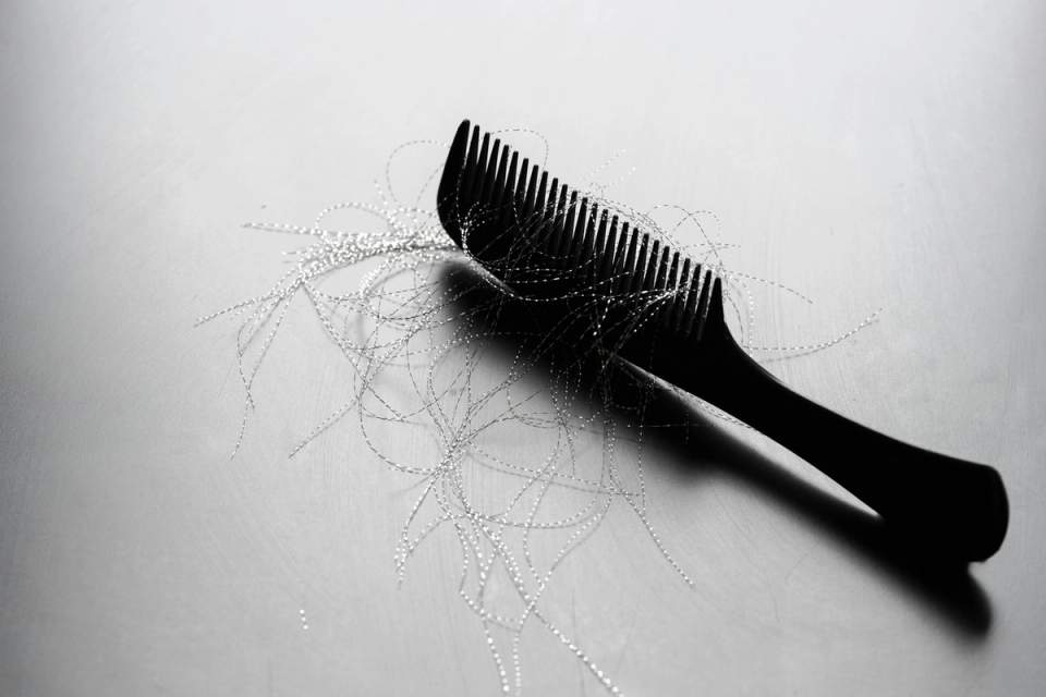 Black comb on a gray surface with loose strands of shed hair