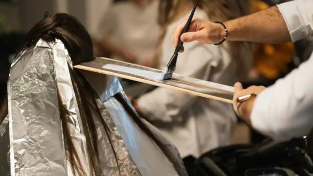 Hair stylist applying hair color using a brush