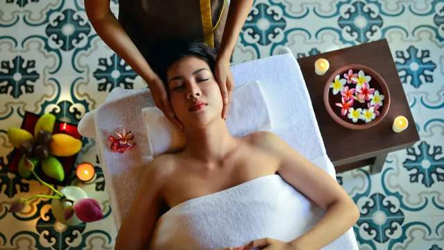 Picture of a woman laying on a massage table and having a head massage